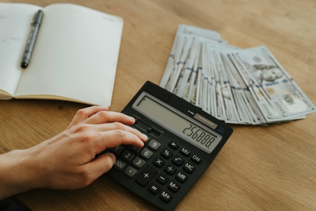 A person using a calculator with money on a table